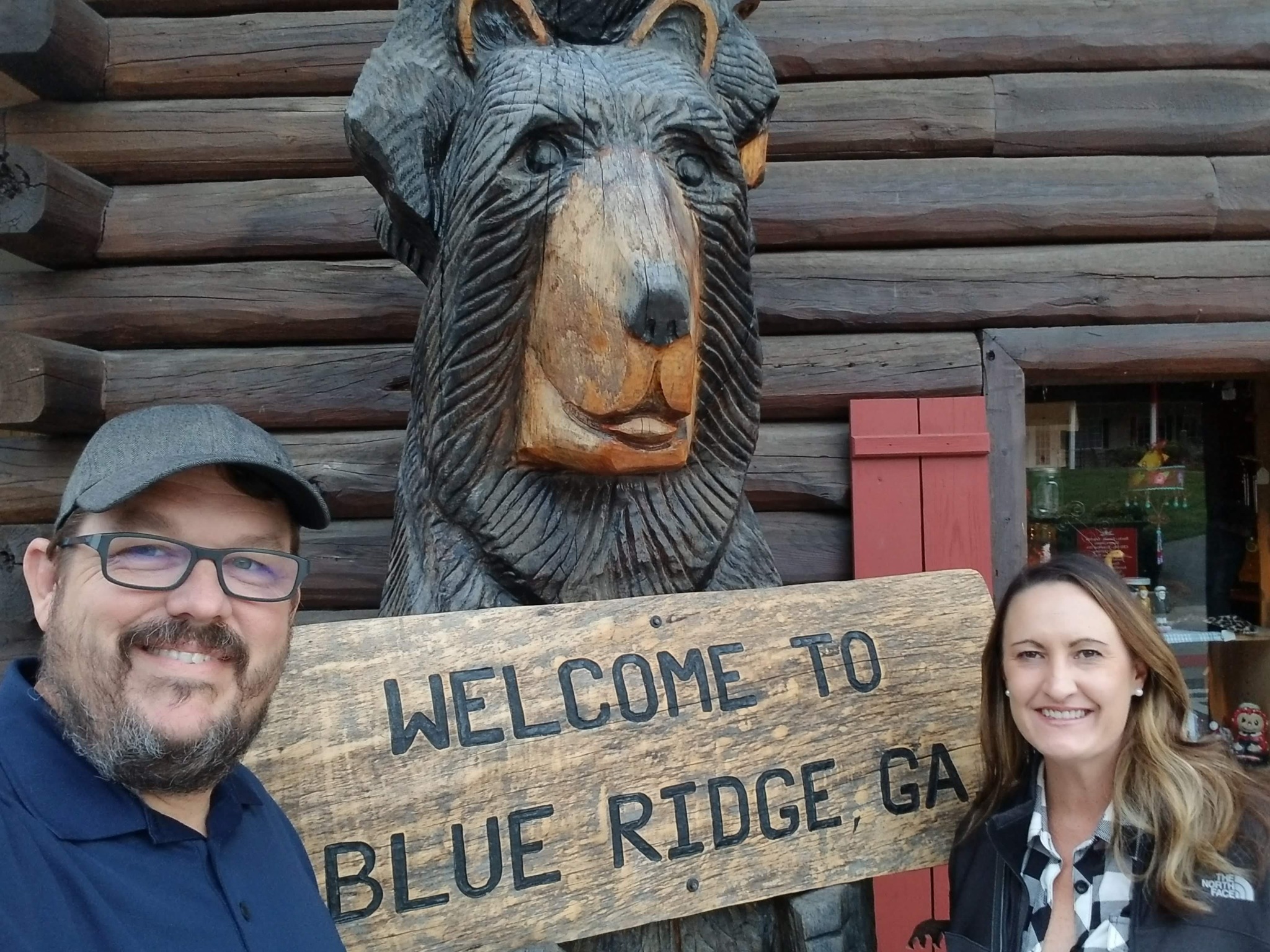 Scott and Kristen beside a carved bear and Welcome to Blue Ridge Georgia sign
