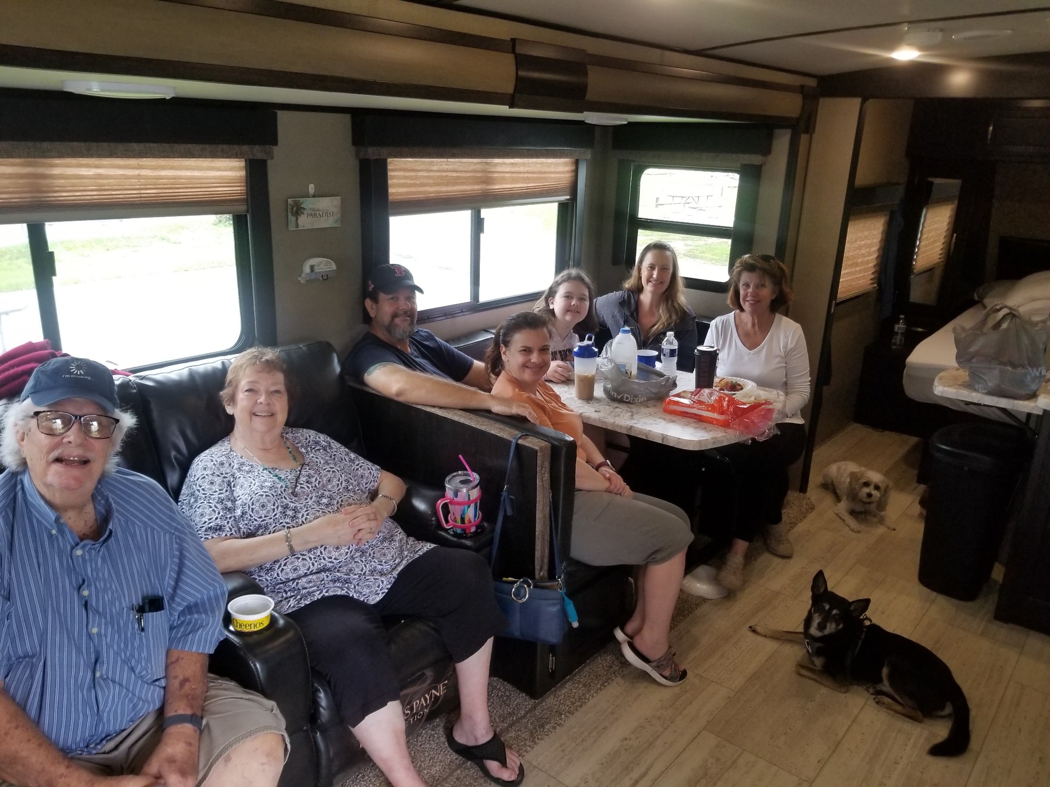 Family gathered around the dinette and sofa inside an RV