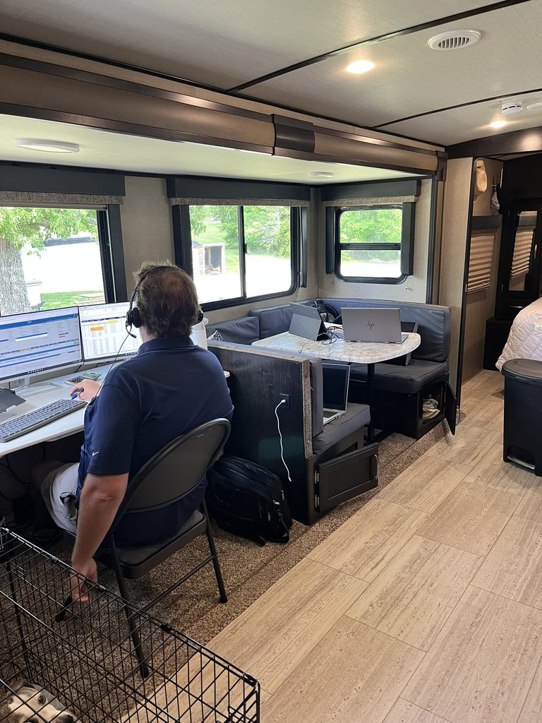 Scott working at a computer inside the RV, with laptops at the dinette